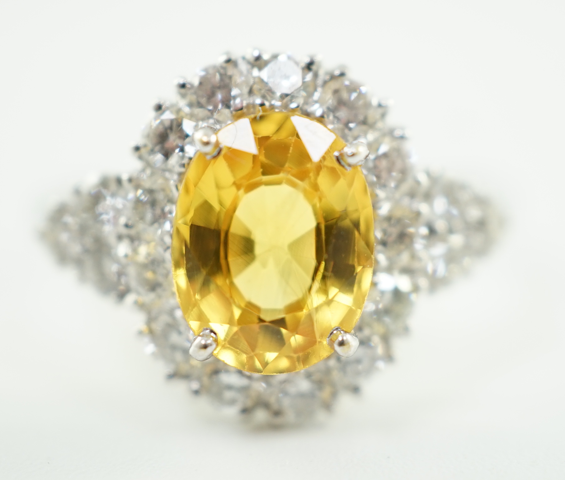 A modern 18ct white gold and single oval cut yellow sapphire set ring